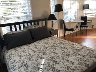 A cozy, inviting bedroom with a floral patterned bedspread and natural light filtering through white blinds